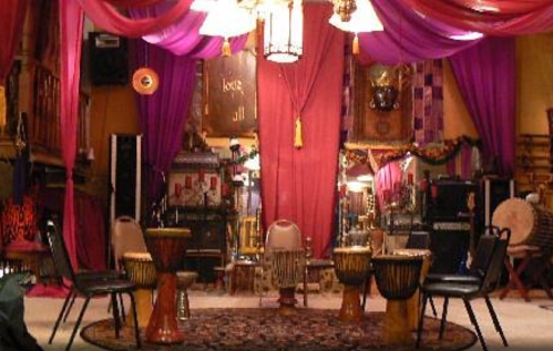 A vibrant room with colorful drapes, drums, and chairs arranged for a musical gathering.
