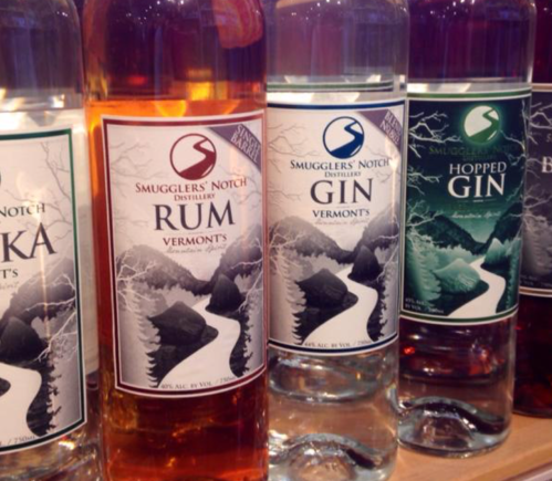 Bottles of Smugglers' Notch spirits, including rum and two types of gin, displayed on a shelf.
