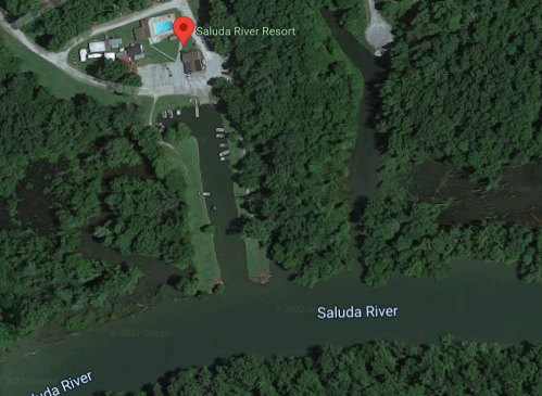Aerial view of Saluda River Resort, surrounded by greenery and the Saluda River, with a pool and parking area visible.