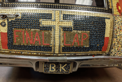 A close-up of a car's rear, decorated with colorful beads and the words "FINAL LAP" prominently displayed.