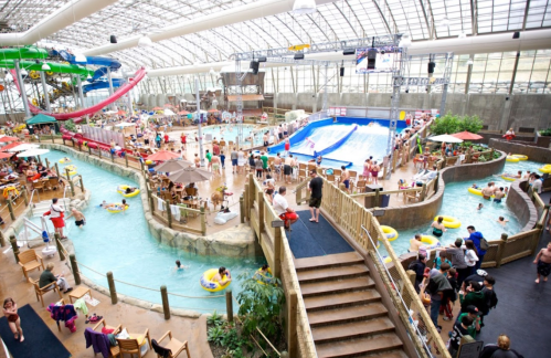 A bustling indoor water park with slides, a wave pool, and numerous visitors enjoying various attractions.