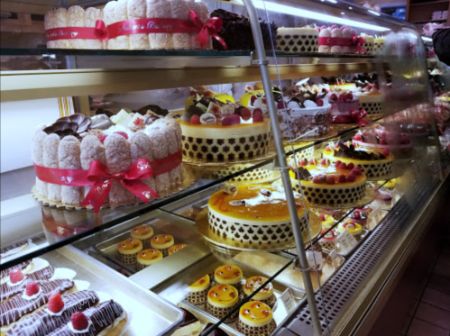 A display case filled with various colorful cakes and pastries, beautifully arranged with decorative toppings.