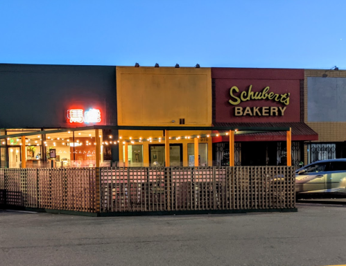 Exterior of Schubert's Bakery at dusk, featuring outdoor seating and illuminated signage.