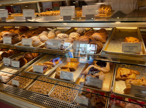A display case filled with various baked goods, including pastries, croissants, and fruit tarts.