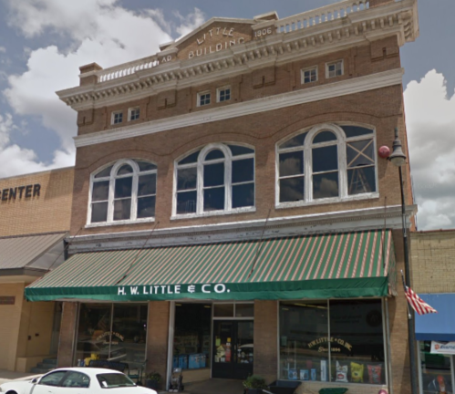 Historic brick building with large windows and a green awning, featuring "H.W. Little & Co." signage.