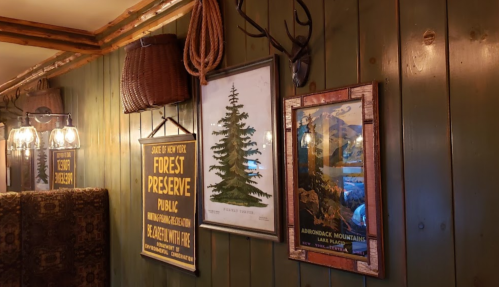 A rustic wall featuring vintage nature-themed posters and antlers, with a green wooden backdrop.
