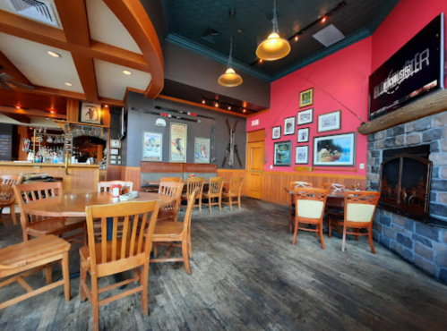 Interior of a cozy restaurant featuring wooden tables, chairs, a stone fireplace, and colorful wall decor.