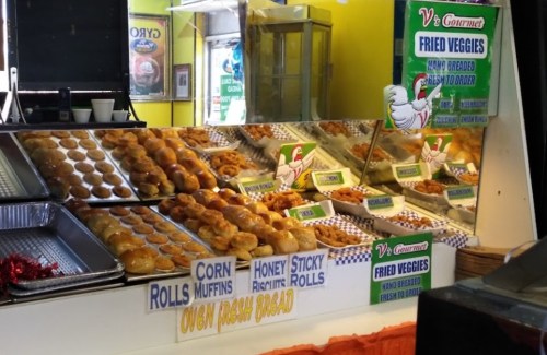 A display of various baked goods, including corn rolls, muffins, and sticky rolls, at a food stall.