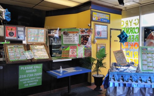 Interior of a restaurant with menus, a waiting sign, and decorations, featuring a table with a blue tablecloth.