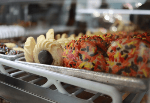 A display of colorful cookies and pastries, including sprinkles and chocolate, in a bakery case.