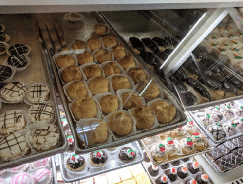 A display case filled with various pastries, including cream puffs and chocolate-covered treats.