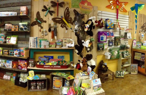 A colorful children's bookstore display featuring books, puppets, and playful decorations on the walls.