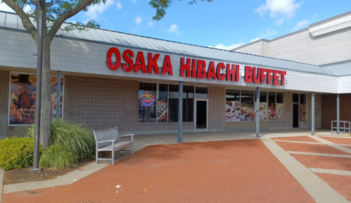 Exterior of Osaka Hibachi Buffet with large red signage and images of food on the windows. Benches in front.