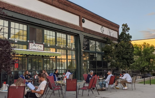 Outdoor dining scene at a restaurant with patrons seated at tables, enjoying a pleasant evening.