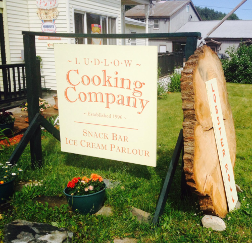 Sign for Ludlow Cooking Company, featuring a snack bar and ice cream parlour, with a wooden lobster roll sign nearby.