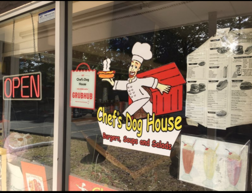 A storefront window displaying "Chef's Dog House" sign with menu items and an "Open" sign.
