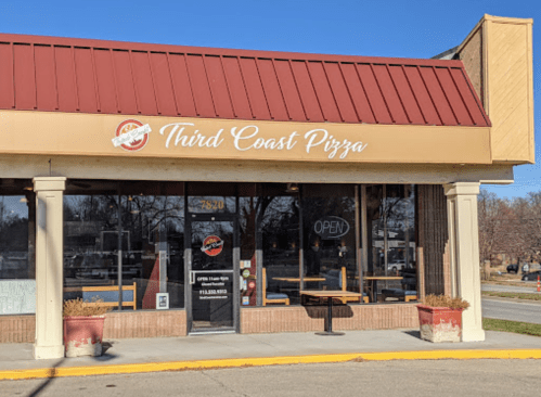 Exterior of Third Coast Pizza restaurant with a red roof, open sign, and large windows on a sunny day.