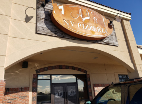 Sign for AJ's NY Pizzeria on a building exterior, featuring a wooden design and large windows.