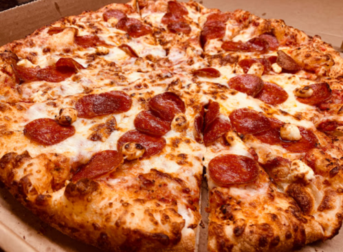 A close-up of a pepperoni pizza with melted cheese, sliced and presented in a pizza box.