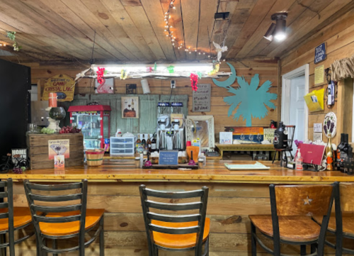 Cozy bar interior with wooden walls, a colorful decor, and empty stools lined up at the counter.