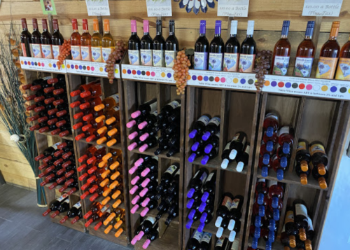 A wooden wine display featuring various bottles of red, white, and rosé wines arranged on shelves.