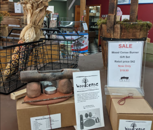 Display of a wood burner gift set with a sale sign, surrounded by rustic decor and baskets.