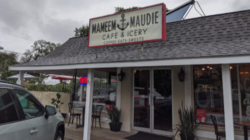 Exterior of Mameem Maudie Café and Icery, featuring a sign and an open flag, with a cozy, inviting atmosphere.