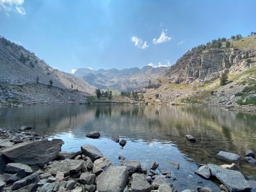 A serene mountain lake surrounded by rocky shores and towering peaks under a clear blue sky.