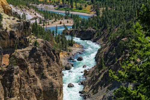 A scenic view of a river winding through rocky cliffs and lush greenery in a mountainous landscape.