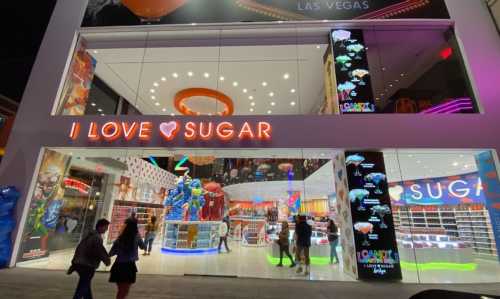 A brightly lit candy store in Las Vegas with colorful displays and a sign that says "I LOVE SUGAR."