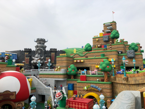 Colorful theme park area inspired by a video game, featuring hills, trees, and playful structures.