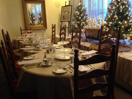 A beautifully set dining table with elegant tableware, surrounded by festive Christmas trees and warm lighting.