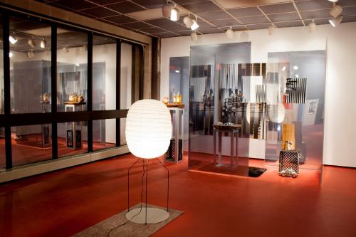 A modern art gallery featuring a unique lamp, reflective surfaces, and abstract artworks on display.