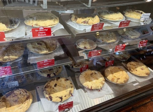 A display case filled with various pies, labeled with flavors like cherry, rhubarb, and apple.