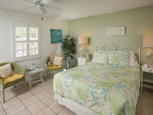 Cozy bedroom with a green accent wall, a queen bed, tropical decor, and seating area with plants and natural light.
