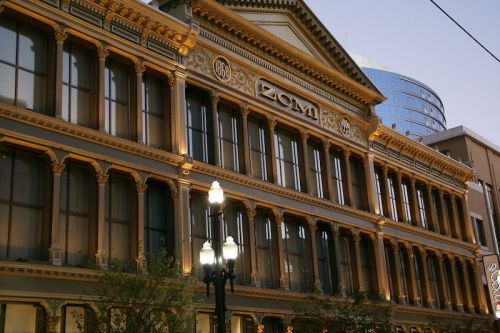 Historic building facade with ornate architecture, featuring the year 1886 and illuminated at dusk.