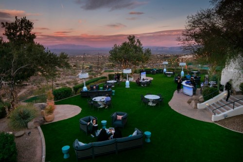 Outdoor event space at dusk, featuring seating areas, a bar, and scenic views of the landscape and sunset.