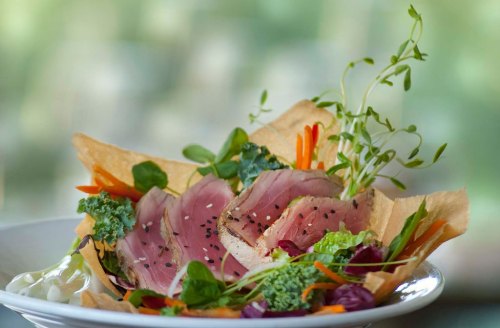 A vibrant salad featuring sliced tuna, mixed greens, and colorful vegetables in a crispy bowl.