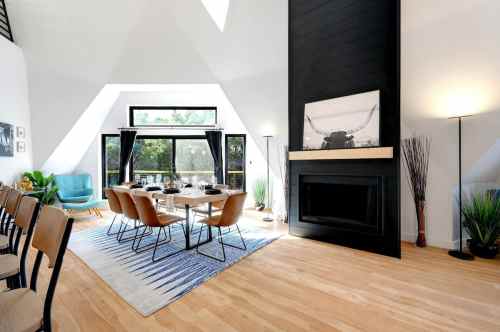 Modern dining area with a large table, stylish chairs, a fireplace, and large windows letting in natural light.