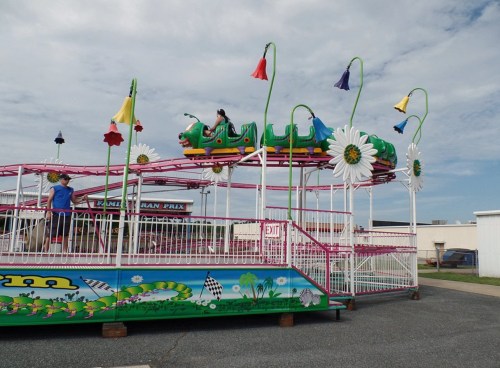 A colorful amusement park ride with flowers and a caterpillar design, set against a cloudy sky.
