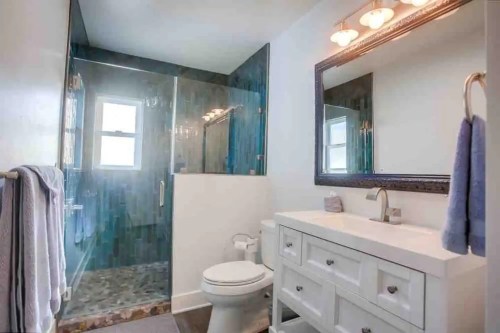 Modern bathroom featuring a glass shower, white vanity, and stylish lighting.
