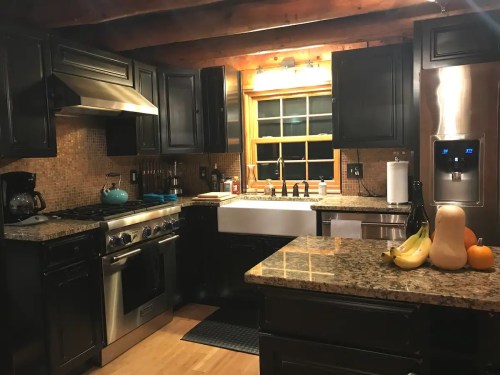 Cozy kitchen with dark cabinets, granite countertops, a farmhouse sink, and a window overlooking the outdoors.