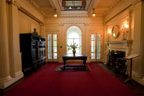 Elegant foyer with a red carpet, ornate furniture, and large windows letting in natural light.