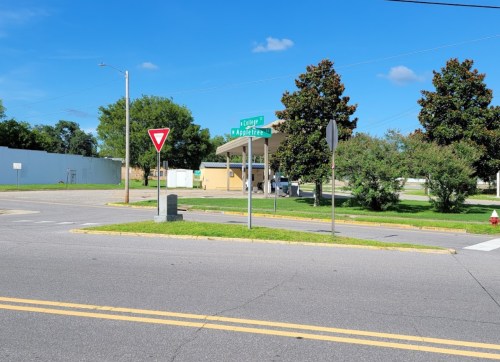 A street intersection with a yield sign and directional signs for "Cedar" and "Applegate," surrounded by greenery.