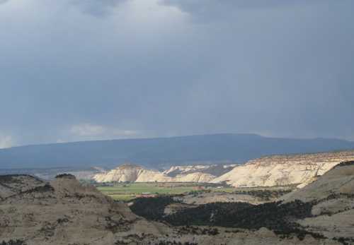 A scenic view of layered mountains and valleys under a cloudy sky, showcasing natural geological formations.