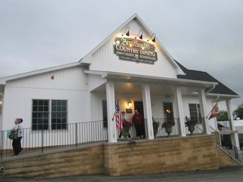 Exterior of Breitbach's Country Dining, a white building with a sign, flags, and a welcoming entrance.