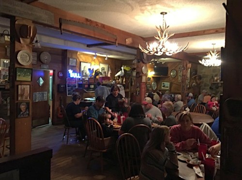 A cozy restaurant interior with wooden decor, patrons dining at tables, and a warm, inviting atmosphere.