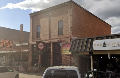 Historic brick building from 1893, featuring storefronts including a burger joint and a gift shop.