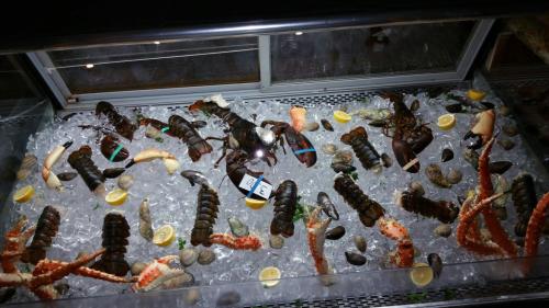 A seafood display featuring lobsters, crab legs, clams, and lemon slices on ice.