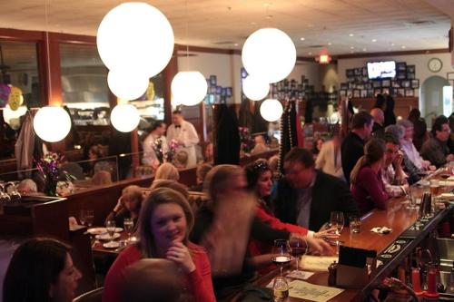 A bustling restaurant scene with patrons at a bar, soft lighting, and festive decorations in a lively atmosphere.